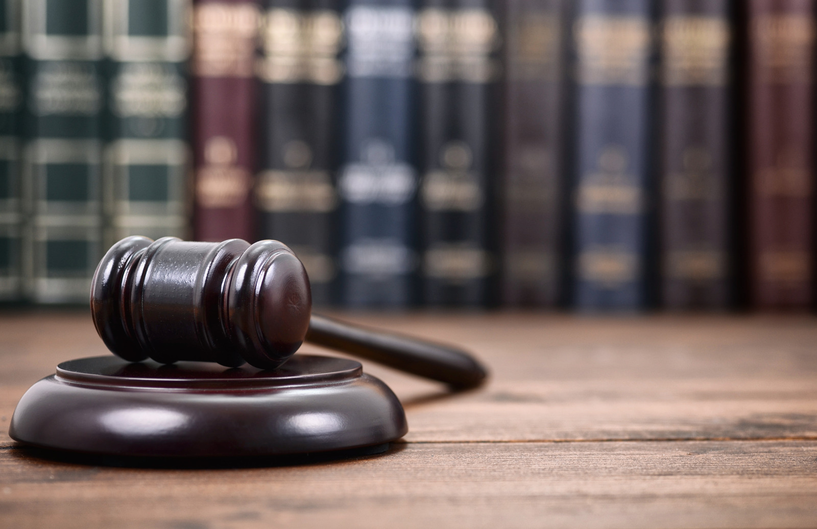 Judge Gavel on a black wooden background in front of law library